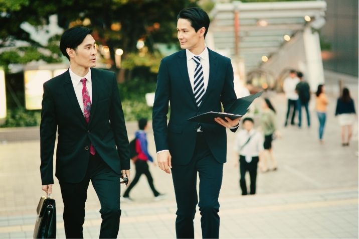 スーツを着たサラリーマンが二人で仕事の話をしながら歩いている